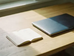 Open adresboek met handgeschreven contacten naast een gesloten laptop op een eikenhouten bureau, zacht ochtendlicht.