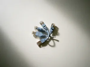 Ethernet- en kabelconnectoren op wit bureau, één stekker half losgetrokken, bovenaanzicht met natuurlijk daglicht.